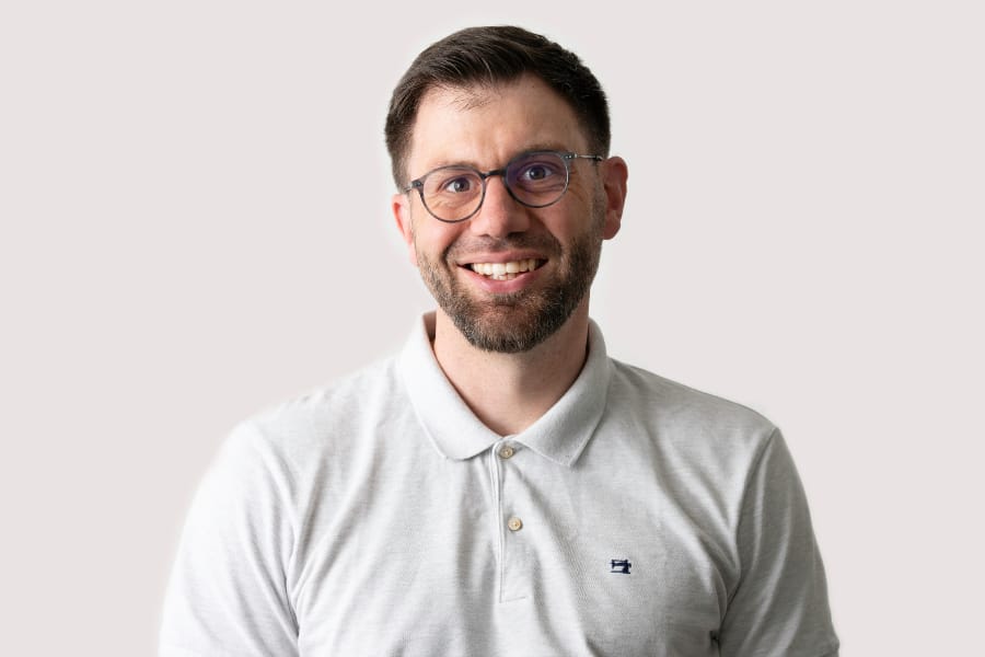 Person mit Brille in einem hellen Polohemd lächelt.