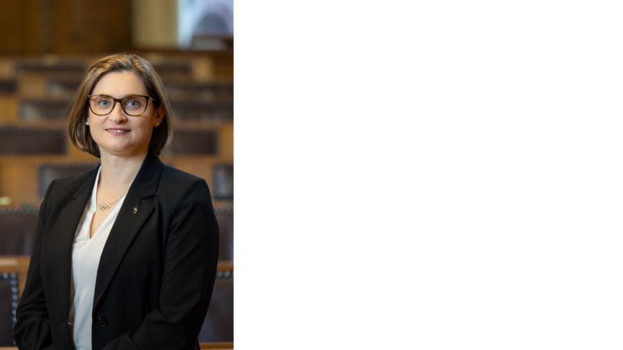 Frau mit Brille in einem Saal stehend.
