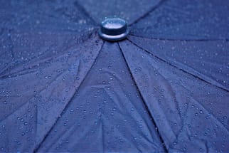 Nahaufnahme eines regennassen blauen Regenschirms.