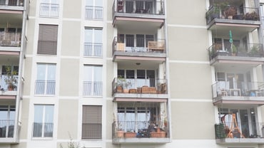 Mehrfamilienhaus mit Balkonen und begrüntem Vordergrund.