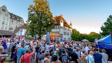 Eine Menschenmenge vor einer Bühne an einem schönen Sommertag. 