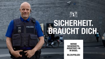 Polizist in Uniform steht vor gemauerter Wand.