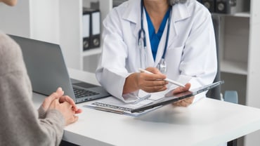 Arzt im Gespräch mit Patient am Schreibtisch.