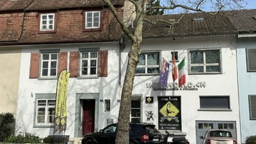 Gebäude mit Werbebannern und geparkten Autos davor.
