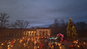 Personen bei Kerzenlicht vor Weihnachtbaum im Friedhof am Hörnli.