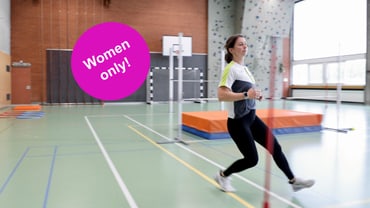 Frau beim Laufen in Sporthalle, lila Schild 'Women only!'
