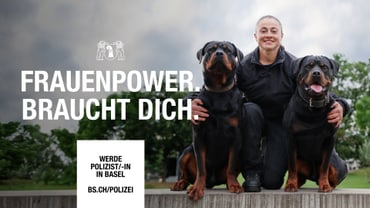 Person in Uniform mit zwei Hunden im Freien.