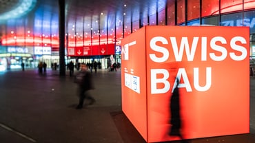 Leuchtendes Swissbau-Logo vor der Messe Basel.