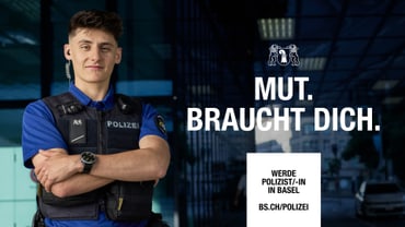 Polizist steht mit verschränkten Armen vor einem modernen Gebäude.