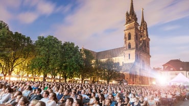 Der vollbesetzte Münsterplatz mit dem Münster im Hintergrund. Alle schauen zur Leinwand, die nicht auf dem Foto sichtbar ist.