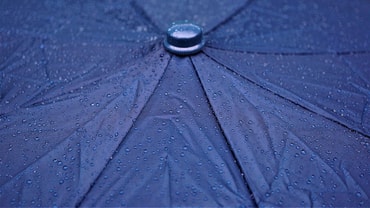 Nahaufnahme eines regennassen blauen Regenschirms.