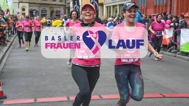 Zwei Frauen im Vordergrund, gefolgt von mehreren Frauen, die am Frauenlauf teilnehmen. 