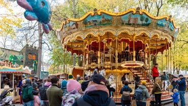 Menschen vor einem beleuchteten Karussell im Park mit Ballon.