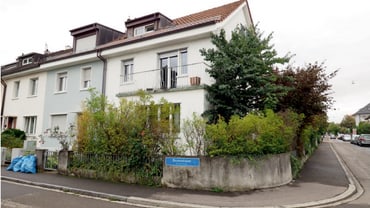 Eckhaus mit Pflanzen und Gehweg in Wohnviertel.