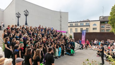 Chor singt draussen vor Publikum in der Stadt.