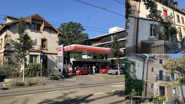 Strassenszene mit Tankstelle und Wohnhäusern.",