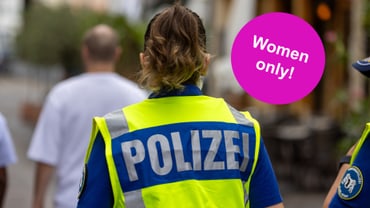 Polizistin mit gelber Weste, Aufschrift 'Polizei', Kreis 'Women only!'.