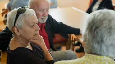 Ältere Menschen am Tisch in einem Gespräch.