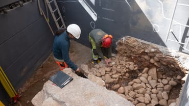 Archäologen arbeiten an Ausgrabung mit Steinen und Werkzeugen.