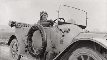 Person in einem alten Auto auf einer Landstrasse.