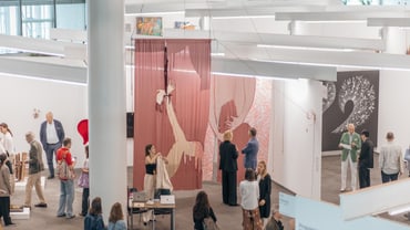 Leute auf einer Kunstmesse mit Gemälden und Installationen.