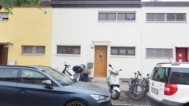 Reihenhäuser mit geparkten Fahrzeugen und Fahrrädern vor der Tür.