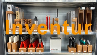 Regal mit Werkzeug und Schreibwaren, orangefarbener Schriftzug 'Inventur'.