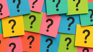 Bunte Karten mit Fragezeichen übereinandergelegt.