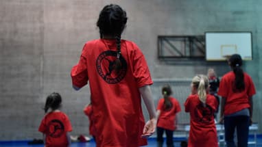 Kinder mit roten T-Shirts in einer Turnhalle.