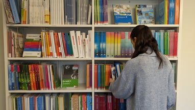 Frau steht vor Bücherregal in einer Bibliothek oder einem Geschäft.