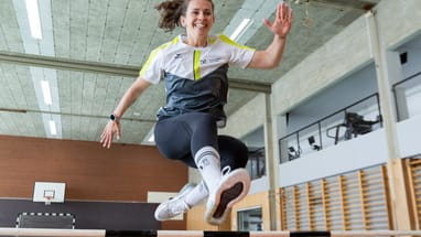 Person springt im Fitnessstudio über eine Hürde.
