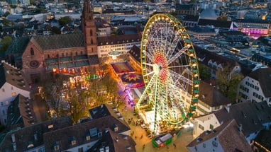 Luftaufnahme des Riesenrads auf dem Basler Münsterplatz bei Abenddämmerung.