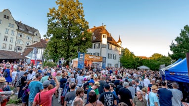 Eine Menschenmenge vor einer Bühne an einem schönen Sommertag. 