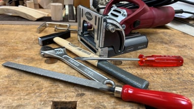 Werkzeuge auf Werkbank, darunter Feile und Schraubendreher.