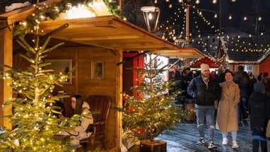 Weihnachtsmarkt mit beleuchteten Bäumen und fröhlichen Besuchern.