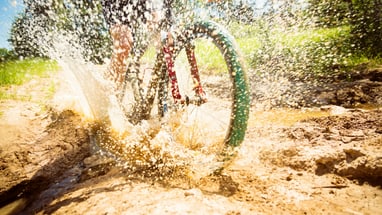 Mountainbiker fährt durch Matsch und Wasser.