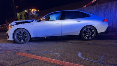 Weisses Auto mit Frontschaden bei Nacht auf Strasse geparkt.