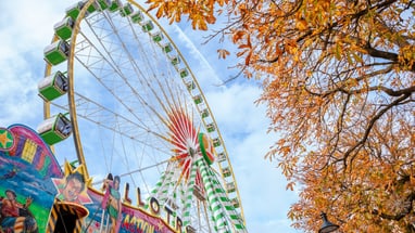 Riesenrad bei Herbstmesse mit bunten Blättern.",