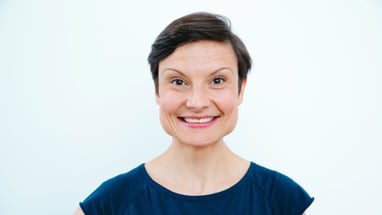 Porträt einer lächelnden Person vor weissem Hintergrund.