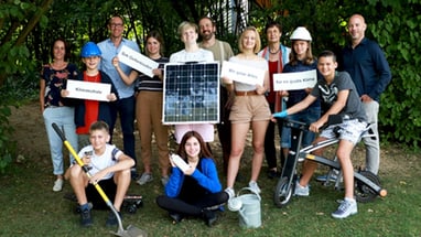 Gruppe von Menschen mit Solarpanel und Schildern im Freien.