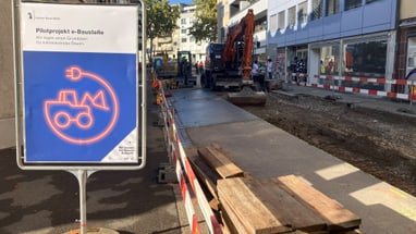 Baustelle mit e-Baustelle Schild und Elektrobagger.