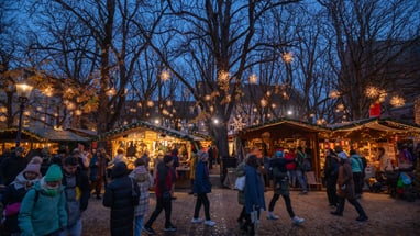 Beleuchtete Weihnachtsmarktstände in der Dämmerung auf dem Münsterplatz.