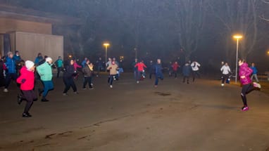 Gruppe von Menschen macht Gymnastik im Freien bei Nachtbeleuchtung.