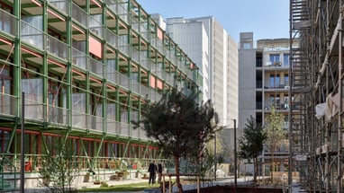 Moderne Gebäude mit grünen Metallstrukturen und Bäumen im Hof.