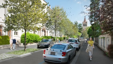 Strasse mit Autos, Bäumen und Kirchturm im Hintergrund.",