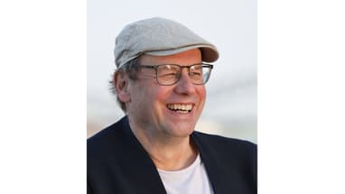 Lächelnde Person mit Brille und Mütze.