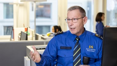 Polizeibeamter in Uniform spricht in einem Büro.