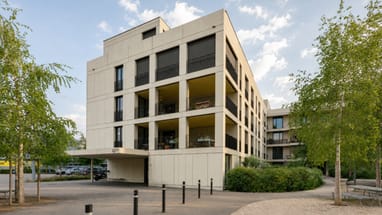 Modernes Wohngebäude mit Bäumen und Gehweg.