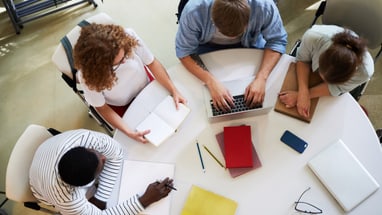 Vier Personen arbeiten zusammen an einem Tisch.