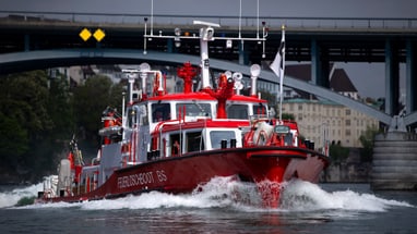 Feuerlöschboot auf dem Fluss vor Brücke in Basel.",